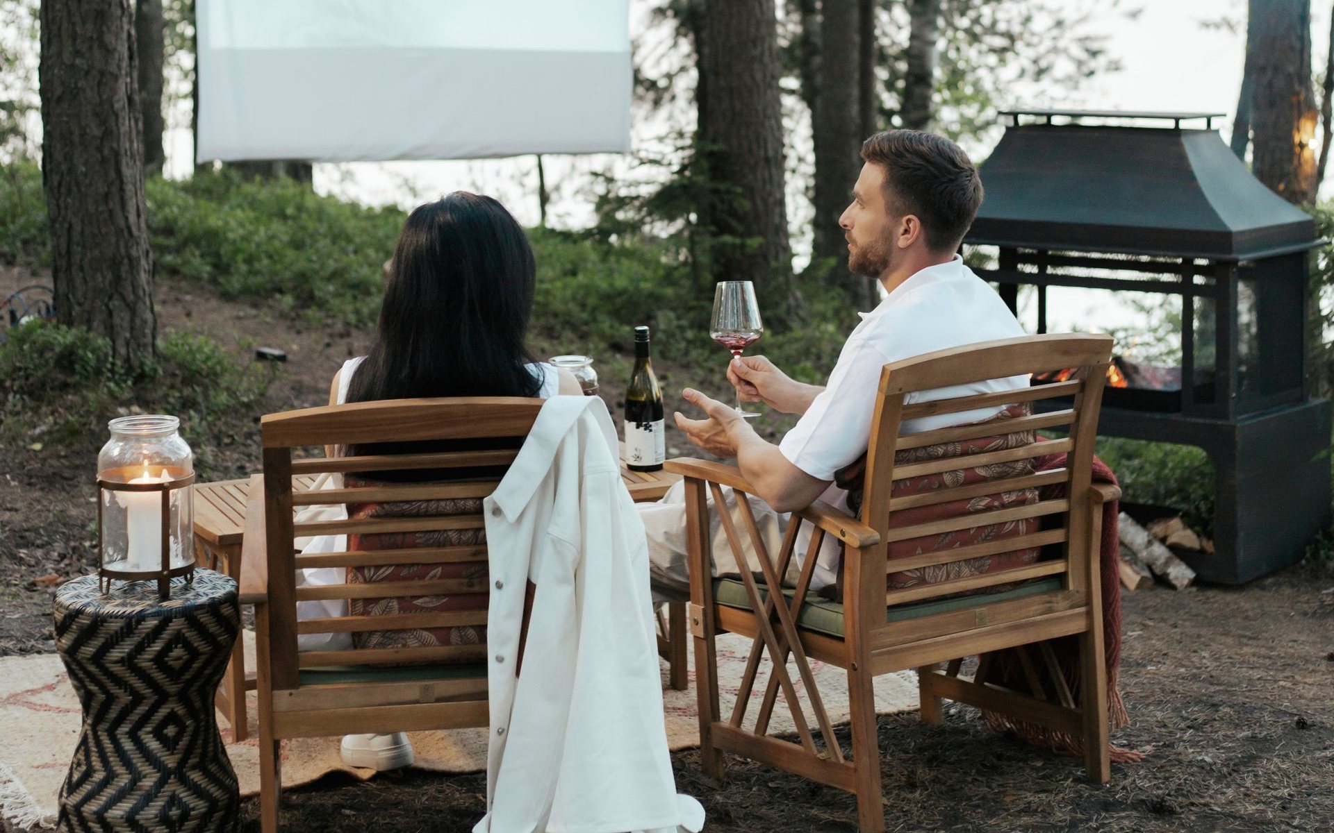 Two people settling in beside the lake as string lights come on at dusk