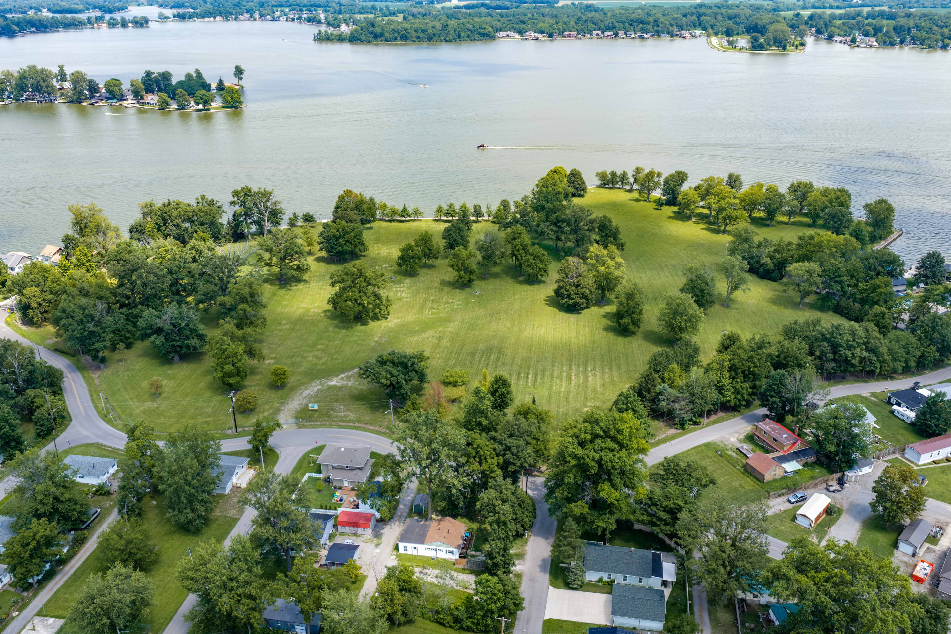 Daylight aerial of the open land at The Orchard Reserve, its treelines and the edge of Indian Lake