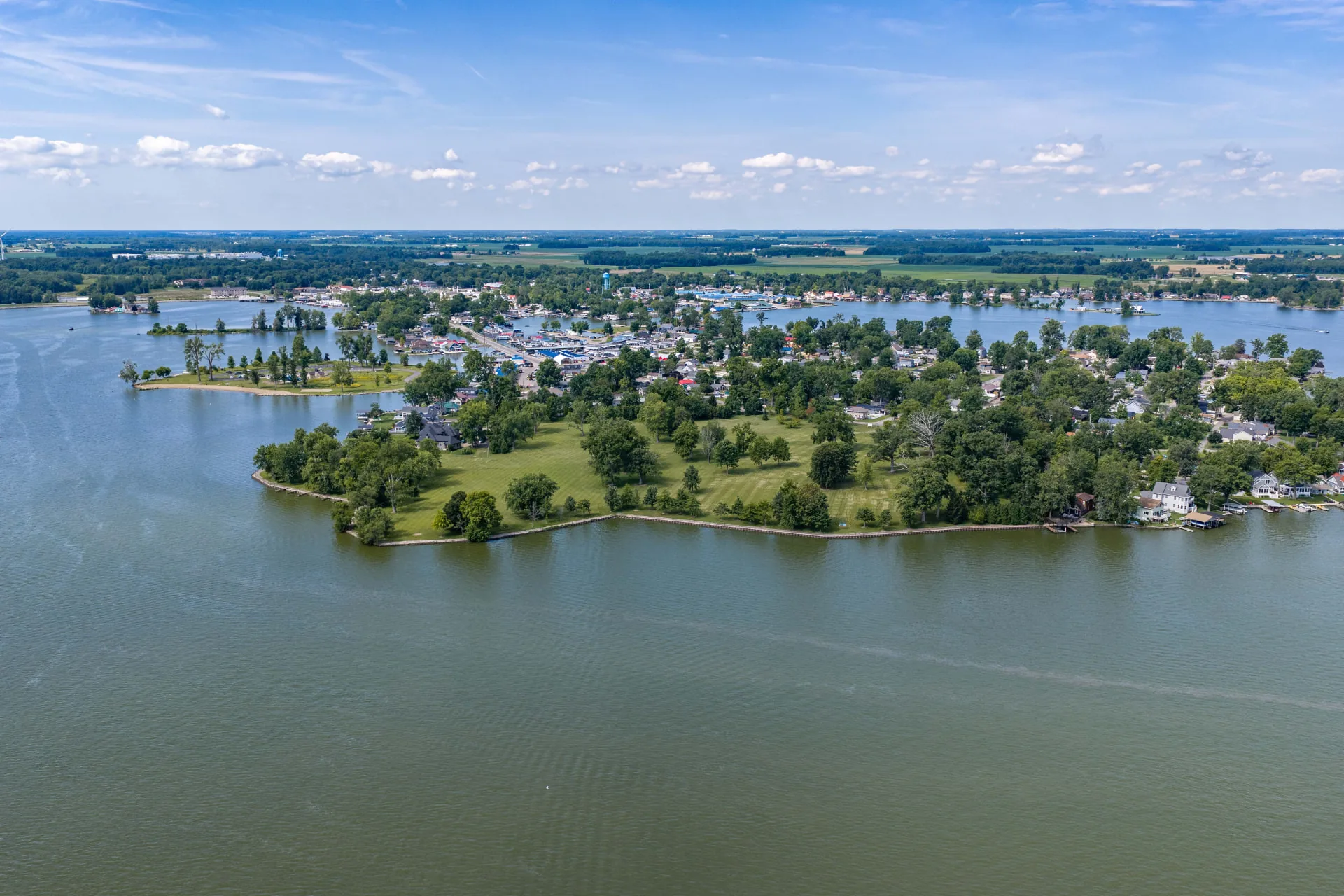 Wide daylight aerial showing Orchard Island reaching into Indian Lake, with the surrounding Ohio farmland on the horizon.